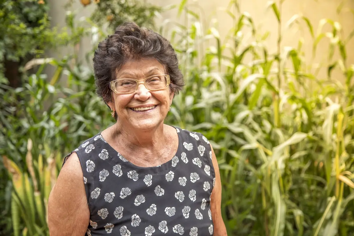 diagnosed with dementia shown through an older woman smiling outdoors in a calm garden setting.
